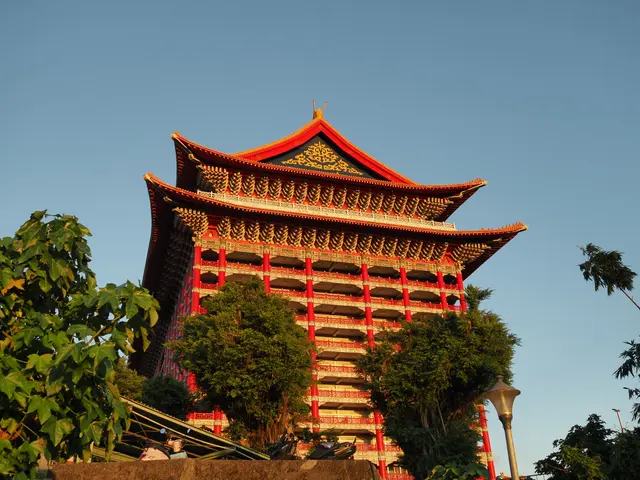 Photographed at Taipei's Grand Hotel, where evening light catches the red columns, golden roof, and layered eaves, setting the main building sharply against the blue sky.