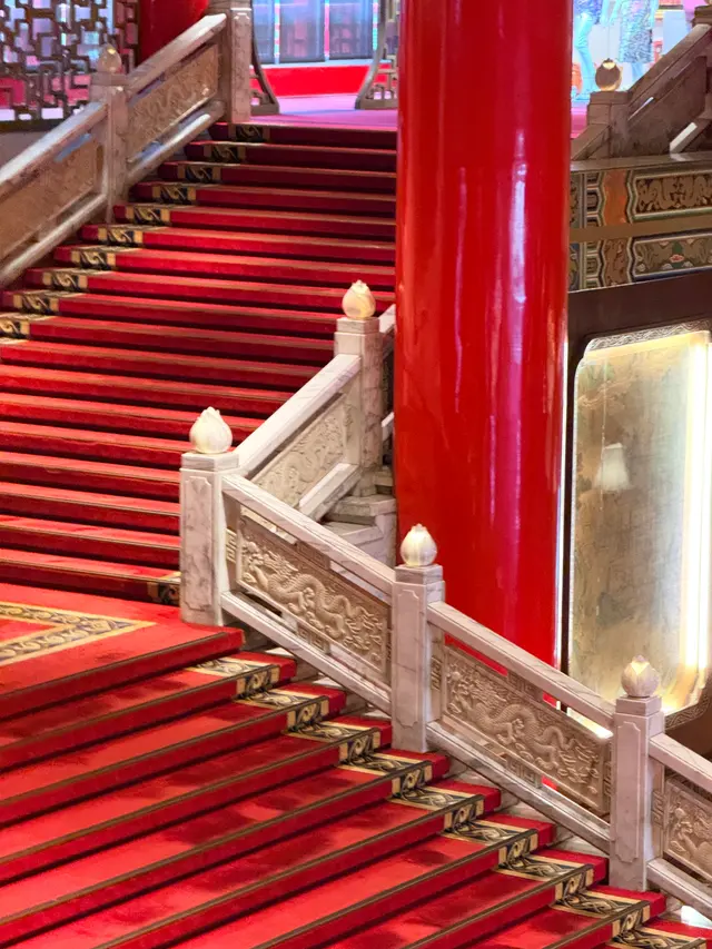 Photographed inside Taipei's Grand Hotel, where red columns and carpeted stairs intersect with carved dragon balustrades beneath the lobby lights.