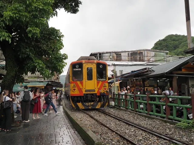 Photographed on Shifen Old Street in New Taipei, where a yellow local train moves slowly past crowds standing close to both sides of the track.