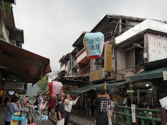 Photographed on Shifen Old Street in New Taipei, where visitors raise a sky lantern covered with wishes beside tracks pressed closely between shops and onlookers.