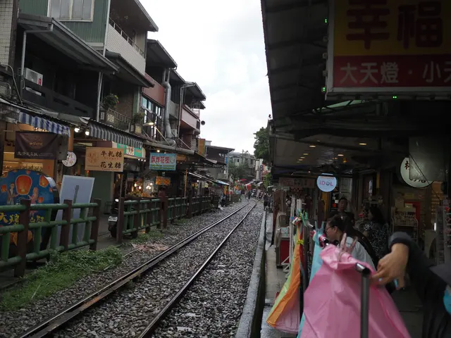 Photographed on Shifen Old Street in New Taipei, where wet railway tracks curve between two rows of shops as sky lanterns and visitors animate the narrow lane.