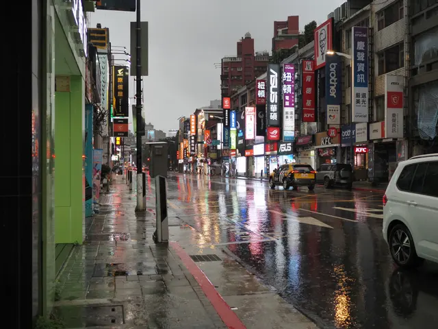 Photographed in Taipei's Guanghua district, where rain glosses the street and reflections from electronics signs and traffic lights stretch into the distance.