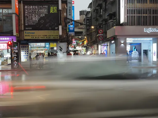 Photographed in Taipei's Guanghua district, where a long exposure turns passing traffic into a pale veil of rain with shop lights glowing behind it.